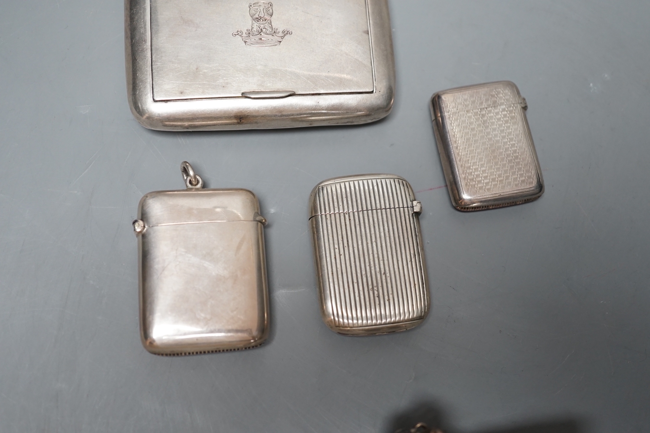 An Edwardian silver snuff box, with engraved crest, Birmingham, 1907, 82mm, three silver vesta cases and an incomplete white metal child's rattle.